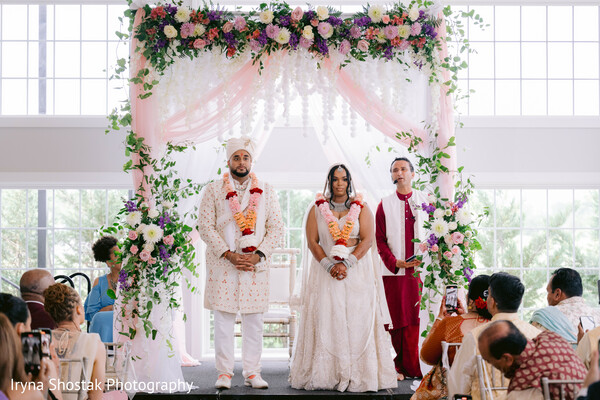 first kiss moment,indian-american wedding ceremony,floral mandap kiss,wedding guests cheering