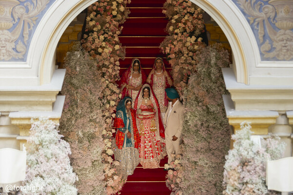 bridal moment on stairs,floral archway wedding,luxury indian wedding,south asian bride,red bridal lehenga