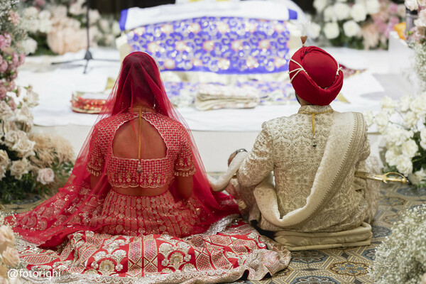 sikh wedding ceremony,wedding from behind,sacred vows,south asian couple seated,red bridal lehenga back
