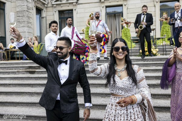 newlywed toast,south asian fusion wedding,outdoor celebration,groom tuxedo bride lehenga,wedding party cheer