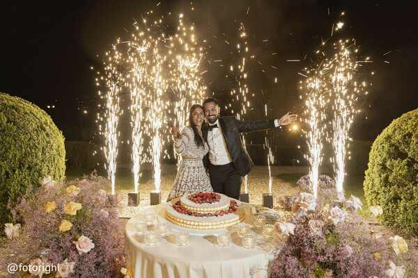 wedding fireworks,cake cutting celebration,outdoor nighttime wedding,romantic wedding moment