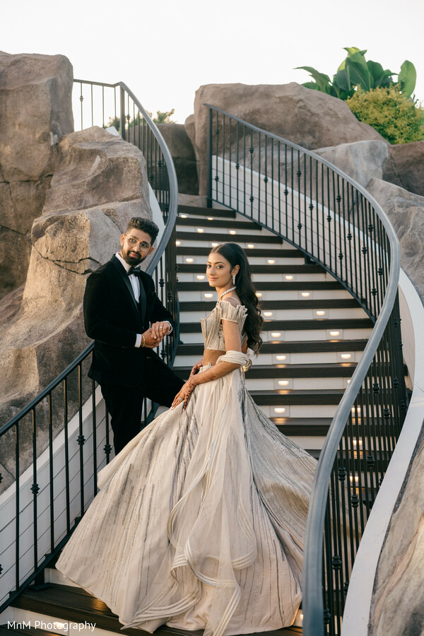 bride and groom staircase pose,silver lehenga and tux,romantic reception photo