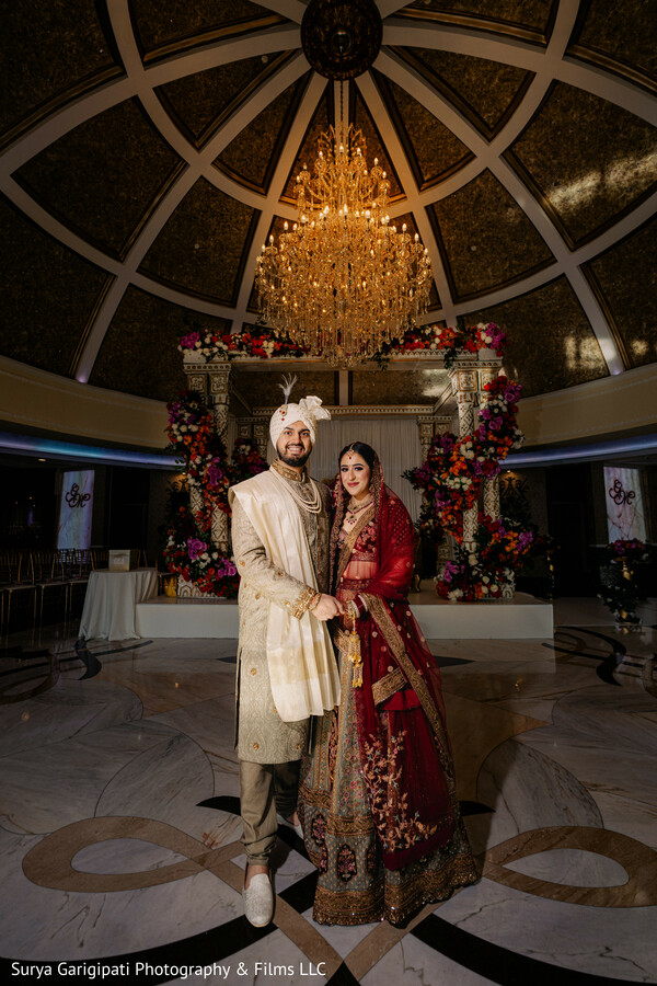 indoor ceremony,wedding chandelier,floral mandap,bride and groom,bridal lehenga