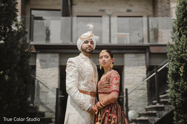 indian wedding couple,regal wedding attire,groom in ivory sherwani,bride in maroon lehenga