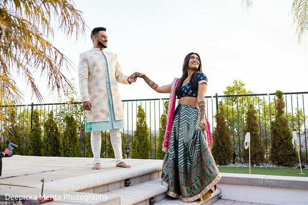 indian couple terrace photo,outdoor wedding walk,bride twirling,playful wedding photo,groom in pastel,vibrant bridal lehenga,romantic moment,candid wedding shot,evening wedding vibe,terrace romance