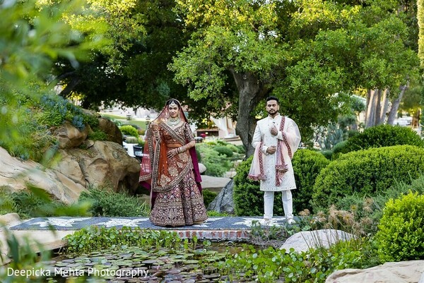 indian wedding walk,couple frontal walking shot,garden ceremony stroll,natural wedding moment,red lehenga bride,groom in sherwani,romantic cultural wedding,couple path photo,elegant wedding movement,lush outdoor shoot