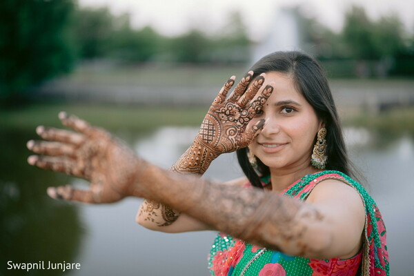 henna detail hands,indian bride mehndi,playful pre-wedding shot,joyful bridal pose,extended hands photo,wedding preparation,traditional bridal look,smiling bride moment,green mehndi attire,cultural celebration
