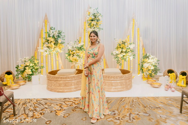 haldi ceremony bride,yellow lehenga indian wedding,floral haldi backdrop,brass decor ceremony,indian pre-wedding ritual,marigold flower stage,joyful bridal portrait,traditional indian haldi,cultural wedding decor,bride in pastel yellow