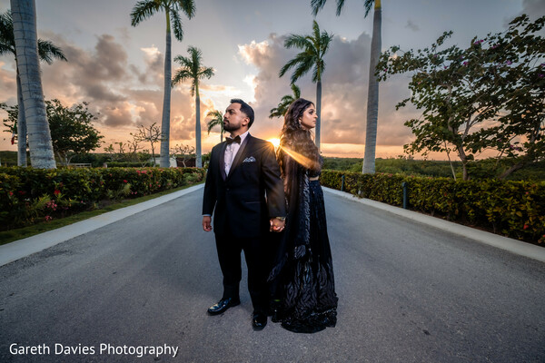 indian couple eveningwear,bride black gown groom tux,destination fashion wedding,tropical road couple pose,sunset wedding fashion,high-end wedding portrait,cultural elegance tropical,black dress wedding photo,indian couple editorial look,wedding finale style