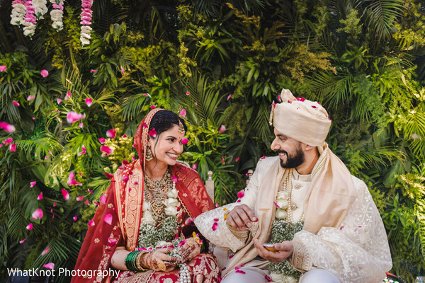 indian couple laughing garden,candid bride groom joy,tropical wedding moment,red lehenga candid photo,groom turban casual pose,couple laugh candid,floral indian wedding portrait,joyful wedding moment,greenery wedding backdrop,cultural love candid