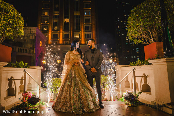 nighttime wedding kiss,indian couple under sparklers,luxury wedding moment,romantic city wedding photo,gold gown bride,urban wedding backdrop,wedding kiss under lights,indian bride groom romance,sparkler celebration shot,magical wedding night