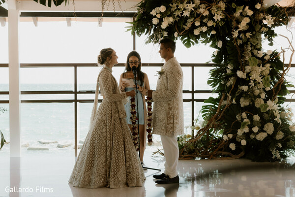 wedding ceremony,floral altar,vow exchange,indoor wedding,ocean backdrop,indian wedding