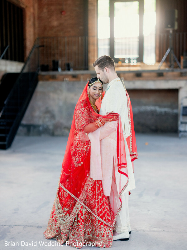 indoor wedding moment,bridal couple,affectionate pose,red bridal outfit,warehouse wedding,modern setting