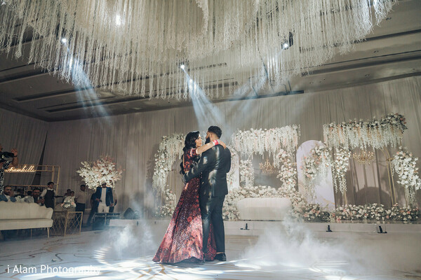 foggy dance floor,reception couple dance,elegant wedding decor,romantic dance moment,golden wedding ambiance,first dance magic,indian wedding reception,dreamy couple moment,red bridal gown,luxury venue vibes