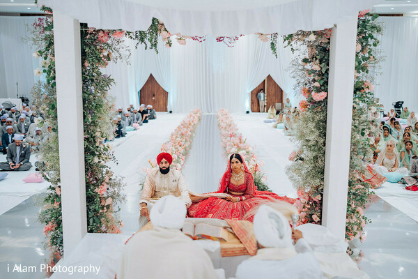 wedding altar design,indian bride at mandap,floral column wedding,white and floral theme,bridal ceremony moment,sikh traditional wedding,indoor mandap elegance,serene altar photo,wedding seat of honor,dream altar