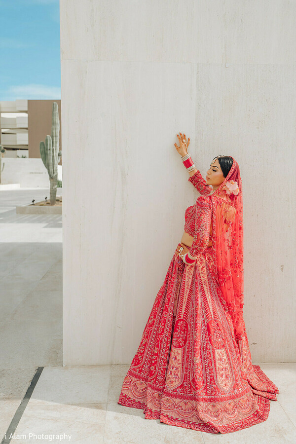 playful bride photo,red lehenga joy,white wall wedding shot,bridal celebration pose,modern bridal photography,lehenga twirl image,sikh bride full pose,indian wedding cheer,joyful bridal fashion,dupatta moment