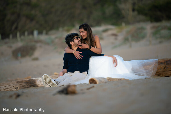 couple beach lounging,romantic coast photo,indian couple on beach,cozy love shot,sand and sea wedding shoot,laid-back bridal shoot,california engagement session,couple relaxed pose,scenic coastal photo,peaceful beach love