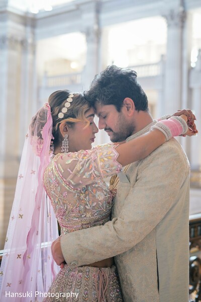 close-up couple hug,marble column wedding photo,romantic embrace shot,soft indian wedding moment,blush lehenga bridal style,groom ivory sherwani,architectural love photo,couple framed by architecture,bridal romance,gentle wedding hug