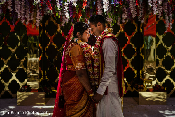 garland exchange ritual,indian wedding ceremony moment,south asian tradition,floral exchange photo,wedding promise gesture,cultural marriage custom,bride groom garland,sacred indian wedding ritual,mandap love moment,wedding flower detail
