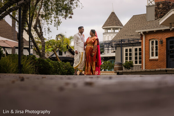 south indian bride walking,courtyard bridal photo,sari wedding elegance,wedding venue walk,bride in red,poise and tradition,outdoor bridal moment,cultural bridal fashion,indian wedding sari walk,heritage in motion