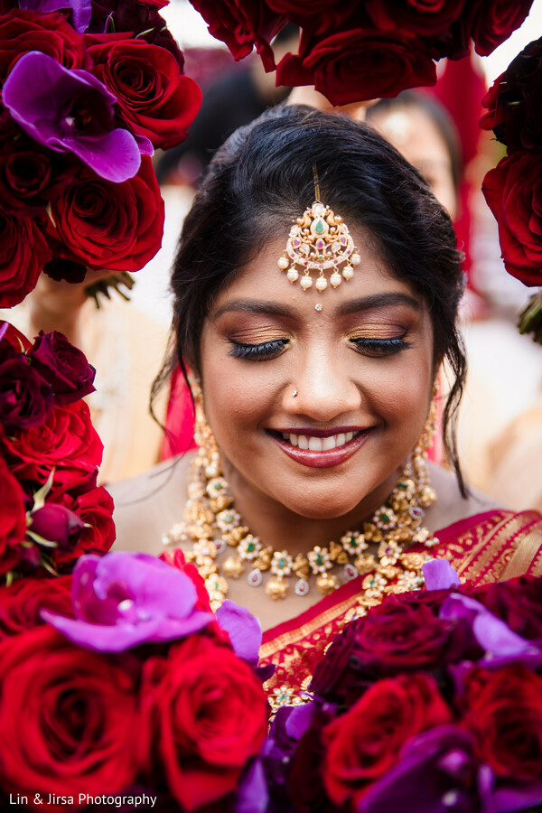 bride in roses,peaceful bridal moment,floral frame photo,indian bridal smile,pink and red roses,bridal joy,south asian bride portrait,wedding serenity,soft bridal beauty,joyful wedding moment
