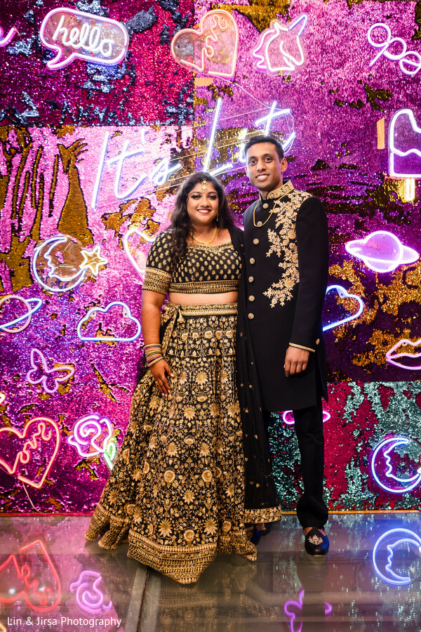 mehndi celebration photo,colorful wedding wall,couple in mehndi decor,vibrant wedding backdrop,south asian couple portrait,traditional event photo,festive couple shot,cultural wedding theme,joyful wedding photo,henna night beauty