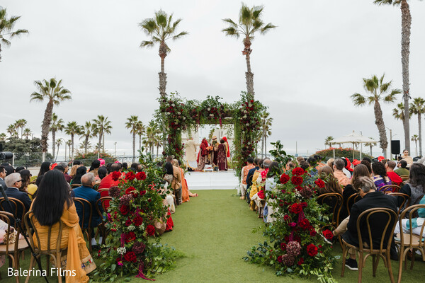 beachside mandap,indian wedding ceremony,tropical wedding,floral mandap design,outdoor hindu wedding,palm tree backdrop,south asian ceremony,red and green florals,aisle moments,destination wedding vibes