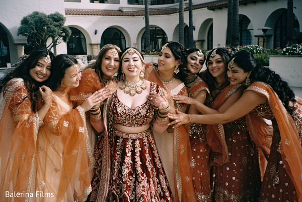 bride squad,bridal glam,red bridal lehenga,bridesmaids in orange,joyful wedding moment,wedding morning,south asian bride,bridal prep fun,group wedding portrait,henna hands
