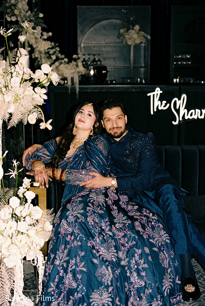 navy blue wedding outfits,embroidered couple looks,luxury wedding lounge,south asian couple,intimate wedding photo,reception glam,modern wedding decor,moody romantic lighting,designer lehenga and sherwani,wedding lounge portraits