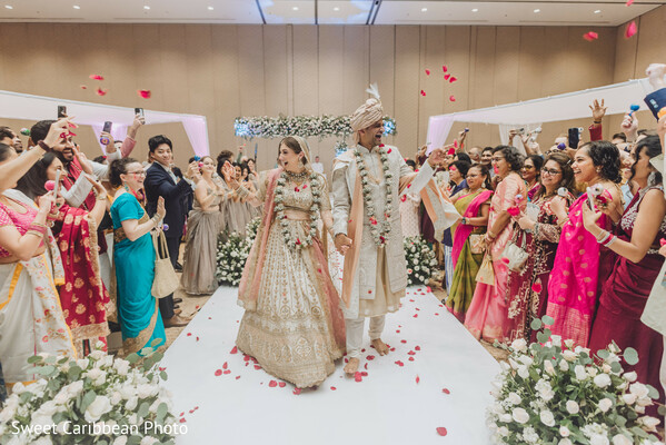 wedding exit,rose petal toss,joyful celebration,bride and groom walk,vibrant saris,aisle moment,indian ceremony,family support,love celebration,indoor wedding venue