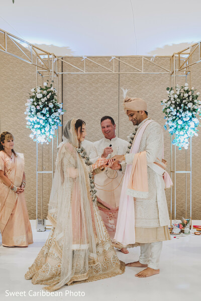 wedding ceremony,indian mandap,vow exchange,bride and groom at altar,pastel decor,spiritual moment,soft lighting,intimate ceremony,traditional vows,hindu wedding ritual