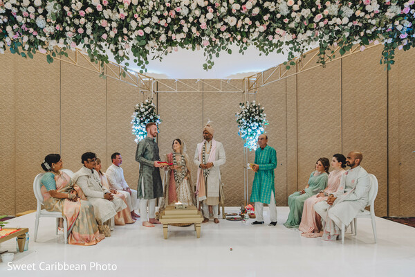 family ceremony,floral mandap,indian wedding ritual,cultural traditions,ceremonial gathering,pastel palette,wedding priest,bride and groom seated,unity moment,intergenerational celebration