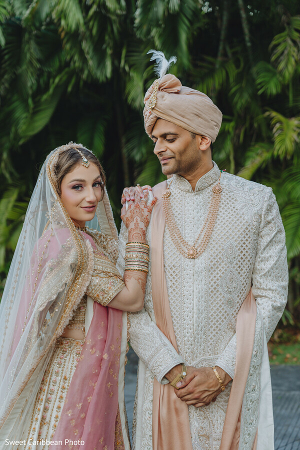 reception stage,bride in white gown,groom in tuxedo,dramatic train,floral backdrop,modern wedding style,romantic lighting,luxury reception,editorial wedding portrait,golden hour glow