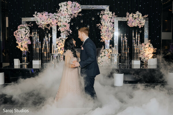 first dance moment,wedding fog effect,romantic dance floor,bride and groom spotlight,floral stage design,indoor wedding dance,magical wedding moment,luxury wedding reception,romantic wedding couple,elegant wedding photography.