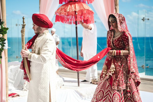 indian wedding ritual,pheras ceremony,seaside mandap,bride and groom moment,wedding traditions,red wedding attire,beachside vows,romanza photography,hindu wedding,ocean wedding