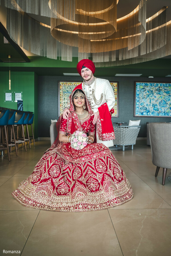 modern wedding venue,indian couple portrait,bridal lehenga,groom sherwani,overhead lighting,fusion wedding look,regal pose,romanza photography,indoor wedding style