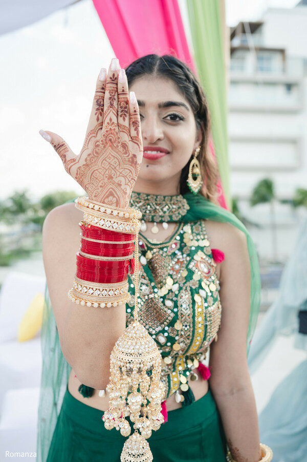 indian wedding guest,festive outfit,green lehenga,mehndi design,wedding bangles,bridal jewelry,pre-wedding celebration,playful pose