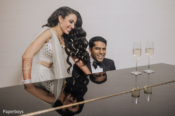 bride and groom,piano moment,candid wedding,joyful couple,champagne wedding,reception style,playful photo,romantic vibe,elegant outfits,indian wedding couple