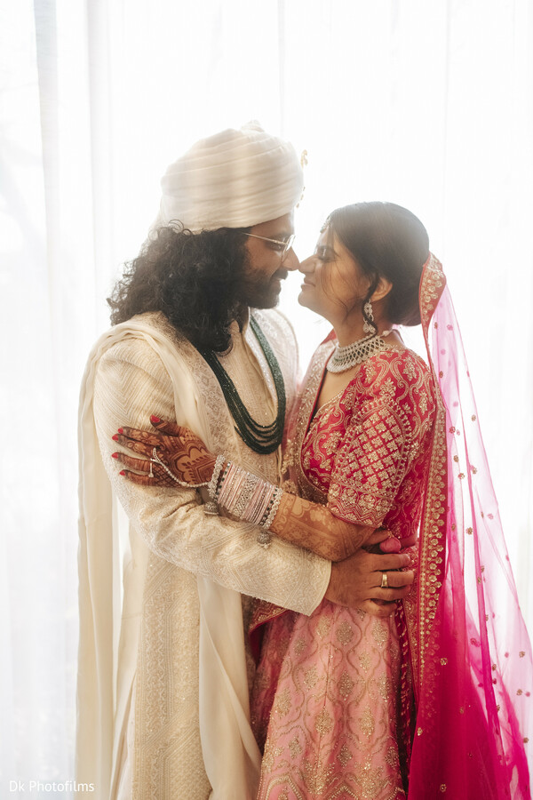 couple embrace,indian bride and groom,pink bridal veil,natural lighting,candid love,romantic portrait,cultural fashion,wedding couple,ivory and pink,tender glance