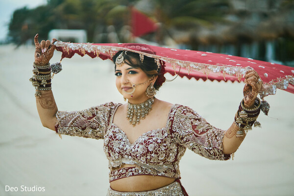beach bridal portrait,dupatta styling,indian bride,oceanfront wedding,embroidered lehenga,playful moment,bridal confidence,destination wedding,coastal shoot,breezy elegance