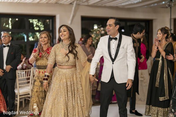 bride and groom dancing,wedding reception,indian wedding joy,bride in gold lehenga,groom in tuxedo,couple dancing moment,candid wedding joy,wedding guests clapping,celebration outfit,dance floor love