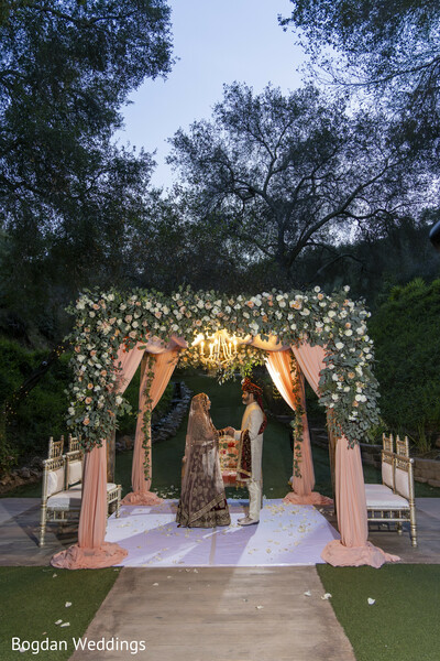 nighttime wedding ceremony,mandap with chandelier,floral wedding arch,outdoor indian wedding,bride and groom vows,romantic mandap setup,wedding under the stars,pastel drapes decor,magical ceremony scene,indian wedding inspiration
