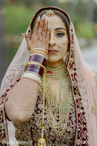 bride mehndi close-up,bridal nose ring,indian bridal portrait,eye cover pose,henna hand pose,dramatic bridal shot,traditional bridal jewelry,maroon bridal lehenga,confident indian bride,creative bridal photograph
