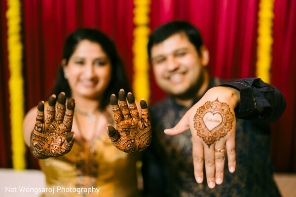 wedding mehndi photo,couple showing henna,heart-shaped mehndi,playful wedding portrait,indian couple celebration,pre-wedding joy,cultural wedding traditions,bride and groom smiles,vibrant wedding photography,fun wedding moment