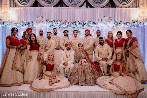 bridal party portrait,groomsmen and bridesmaids,traditional wedding attire,group photo,family and friends,ivory red outfits,wedding stage,south asian wedding,regal wedding party,posed wedding photo