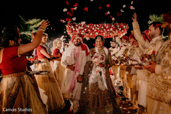 wedding exit,flower shower,celebration walk,joyful couple,traditional wedding,reception ending,bride and groom happiness,wedding aisle moment,night celebration,festive send-off