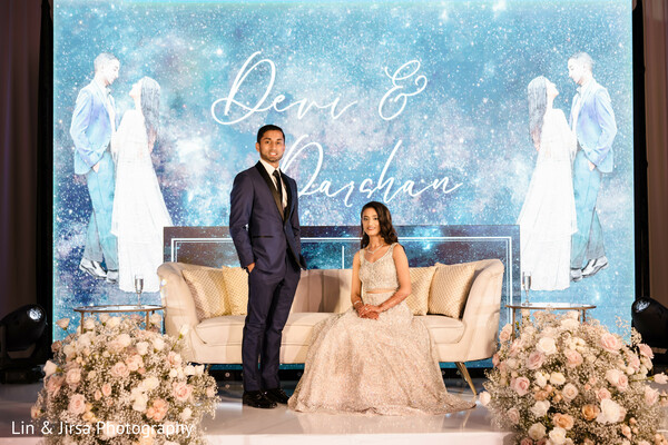 reception stage,luxury wedding decor,glamorous couple,celestial backdrop,wedding portraits,reception elegance,bride and groom style,south asian reception,floral stage,luxury wedding design