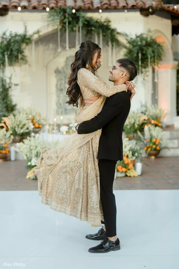 playful wedding moment,groom lifting bride,reception fun,newlyweds celebration,candid wedding laughter,bride in gown,groom’s joy,dance floor fun,lively couple portrait,sweet candid photo