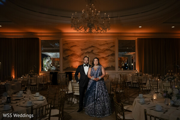 wedding reception portrait,golden reception decor,navy gown bride,elegant groom tuxedo,ballroom wedding photo,luxury wedding interiors,romantic evening reception,south asian couple reception,glamorous wedding vibes,timeless ballroom elegance