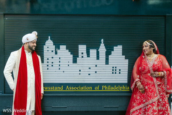 city wedding backdrop,red bridal lehenga,ivory sherwani groom,outdoor wedding portrait,south asian couple photo,modern cultural wedding,colorful city wedding vibe,unique bridal portrait,urban wedding photography,bold wedding love story